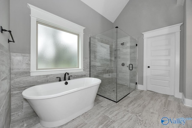 bathroom featuring a shower stall, a soaking tub, tile walls, and lofted ceiling