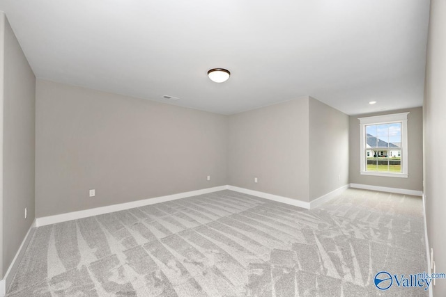 spare room with visible vents, light colored carpet, and baseboards