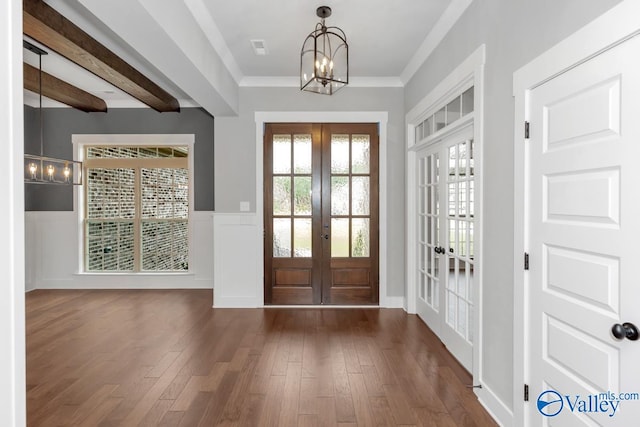 foyer featuring french doors, an inviting chandelier, beamed ceiling, ornamental molding, and dark wood-type flooring