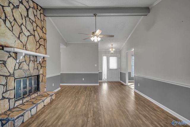 unfurnished living room featuring crown molding, a stone fireplace, vaulted ceiling with beams, and wood-type flooring