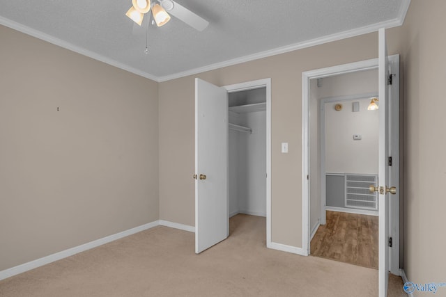 unfurnished bedroom featuring crown molding, ceiling fan, a textured ceiling, light colored carpet, and a closet