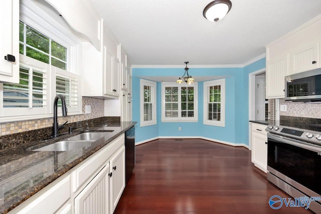 kitchen featuring white cabinets, a sink, an inviting chandelier, decorative backsplash, and appliances with stainless steel finishes