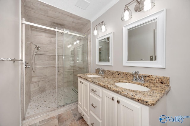 bathroom with double vanity, a shower stall, and a sink