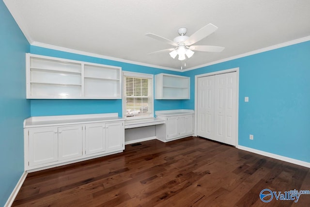 unfurnished bedroom with built in desk, baseboards, a closet, and dark wood-type flooring