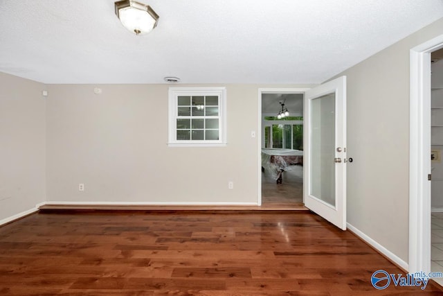 unfurnished room with baseboards, french doors, and wood finished floors