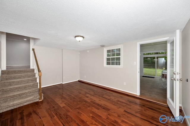 below grade area with stairway, baseboards, wood finished floors, and a textured ceiling