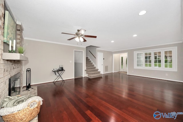 unfurnished living room with stairway, wood finished floors, a brick fireplace, and ceiling fan