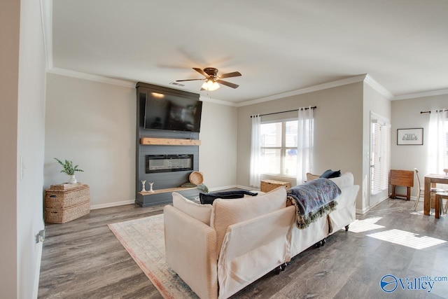 living room featuring hardwood / wood-style flooring, ceiling fan, ornamental molding, and a fireplace