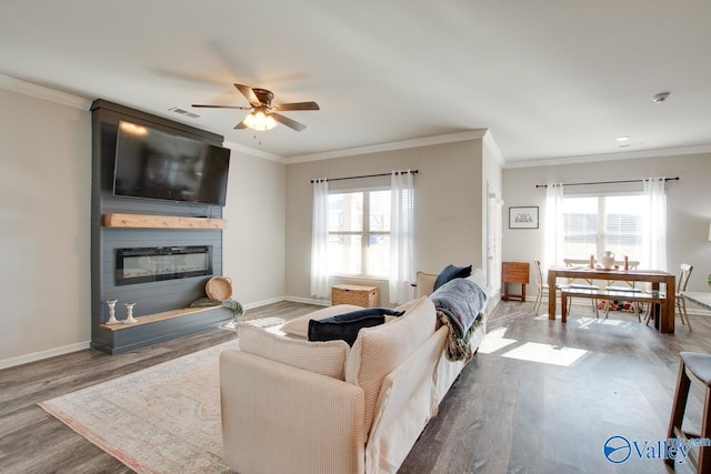living room featuring a fireplace, ornamental molding, hardwood / wood-style flooring, and a healthy amount of sunlight