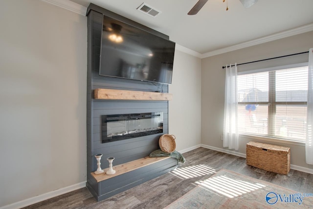living room with a fireplace, ceiling fan, ornamental molding, and dark wood-type flooring