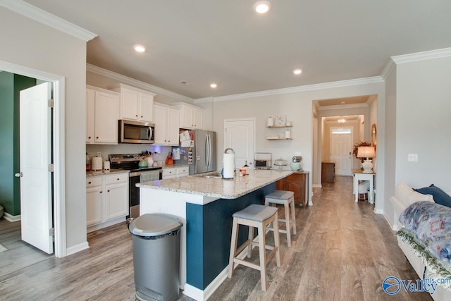 kitchen with white cabinets, appliances with stainless steel finishes, a kitchen breakfast bar, and an island with sink