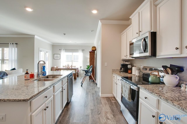 kitchen with a center island with sink, sink, appliances with stainless steel finishes, light hardwood / wood-style floors, and white cabinetry