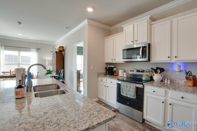 kitchen with appliances with stainless steel finishes, light stone counters, sink, light hardwood / wood-style floors, and white cabinetry