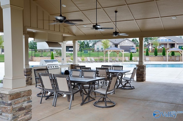 view of patio / terrace with a gazebo, an outdoor kitchen, area for grilling, and a community pool