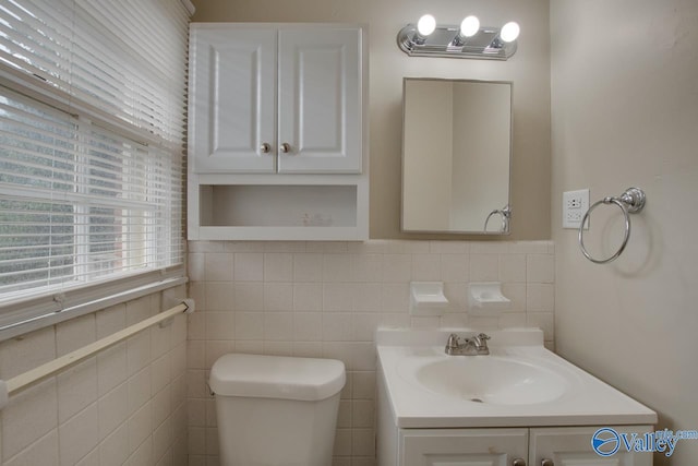 bathroom with vanity, toilet, and tile walls