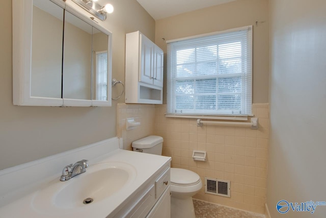 bathroom with vanity, toilet, and tile walls