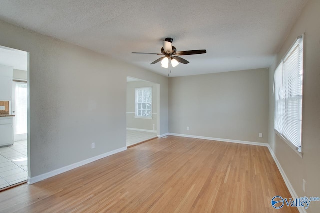 empty room featuring a wealth of natural light, light hardwood / wood-style flooring, and ceiling fan