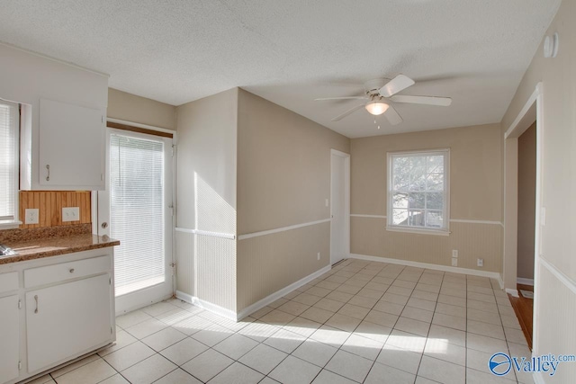 kitchen with white cabinets, ceiling fan, light tile patterned floors, and a textured ceiling