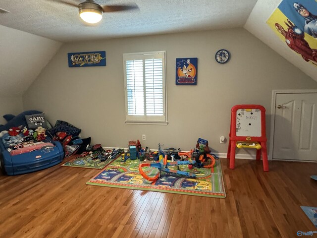 game room featuring ceiling fan, vaulted ceiling, a textured ceiling, and hardwood / wood-style floors