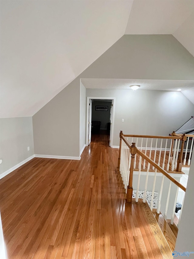 corridor with lofted ceiling and hardwood / wood-style floors