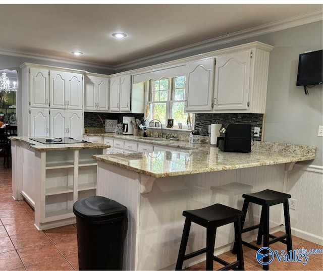 kitchen featuring light stone countertops, kitchen peninsula, sink, and white cabinets