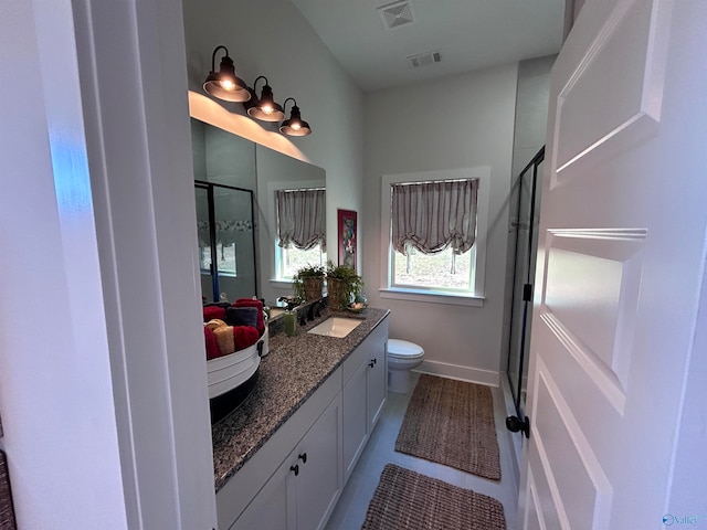 bathroom with tile patterned flooring, vanity, an enclosed shower, and toilet