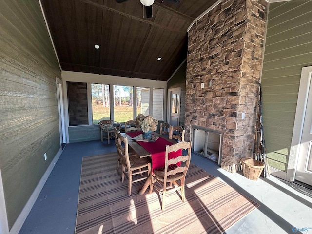 sunroom / solarium featuring an outdoor stone fireplace, vaulted ceiling, ceiling fan, and wood ceiling