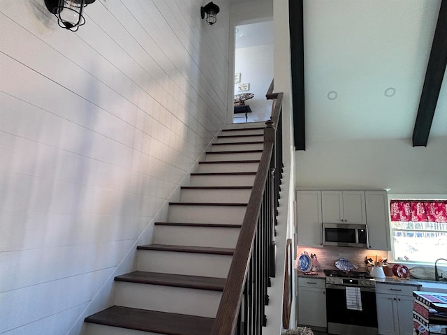 staircase with sink and beam ceiling