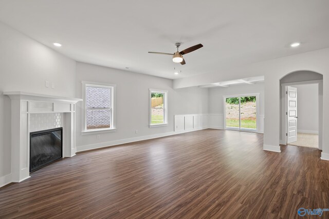 unfurnished living room featuring ceiling fan, dark wood-type flooring, and a tile fireplace