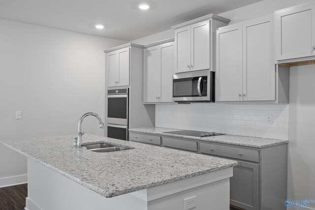 kitchen featuring an island with sink, stainless steel appliances, and light stone countertops