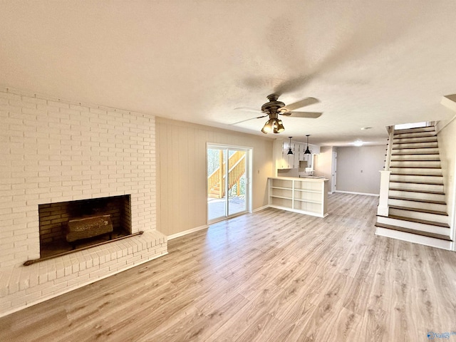 unfurnished living room featuring a textured ceiling, wood finished floors, a ceiling fan, baseboards, and stairway