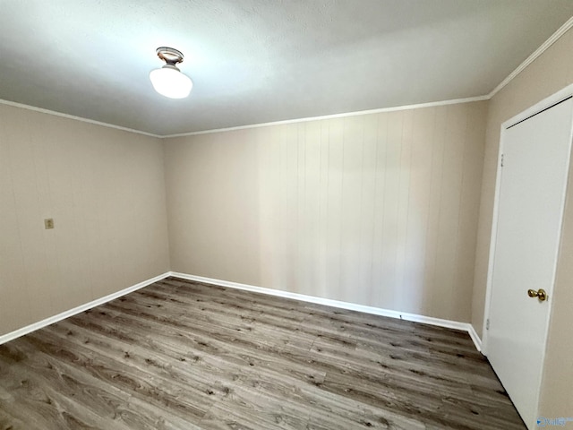 unfurnished room featuring crown molding, baseboards, and wood finished floors