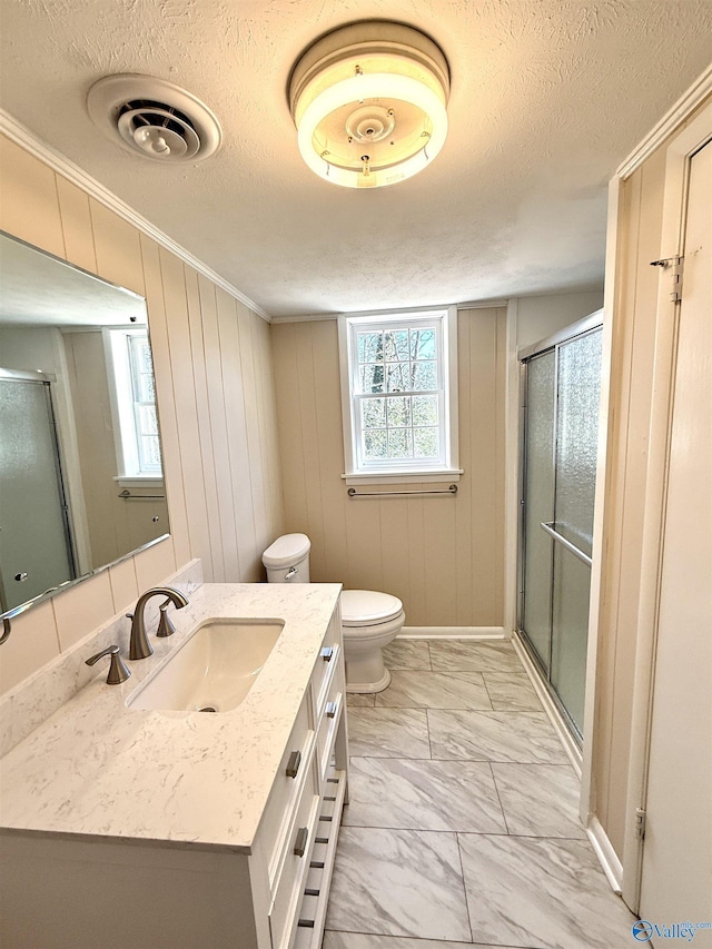 bathroom featuring marble finish floor, vanity, a textured ceiling, and a stall shower