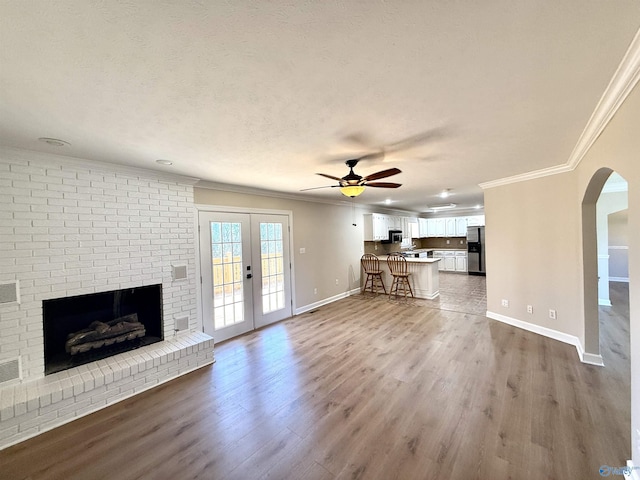 unfurnished living room featuring baseboards, french doors, crown molding, and wood finished floors