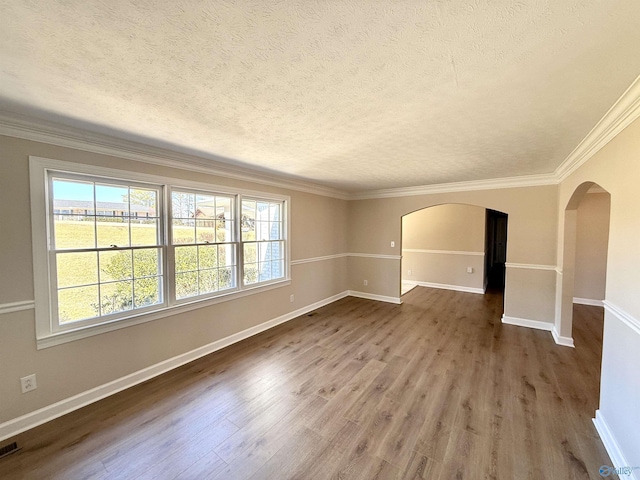 empty room featuring arched walkways, a textured ceiling, baseboards, and wood finished floors