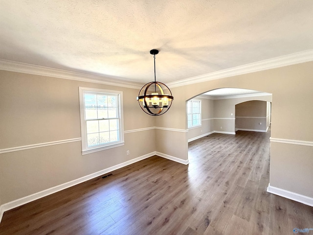 unfurnished dining area featuring a chandelier, arched walkways, plenty of natural light, and wood finished floors