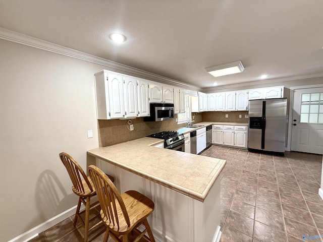 kitchen with stainless steel appliances, a sink, backsplash, and a peninsula