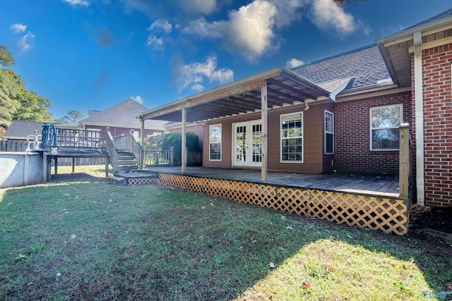 rear view of house featuring french doors, a deck, and a lawn