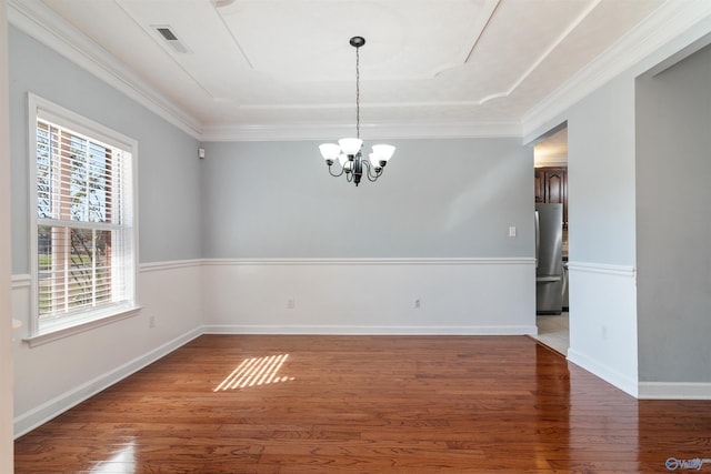 spare room with wood-type flooring, ornamental molding, and an inviting chandelier