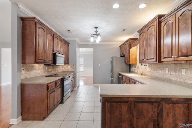 kitchen with kitchen peninsula, appliances with stainless steel finishes, crown molding, sink, and a chandelier