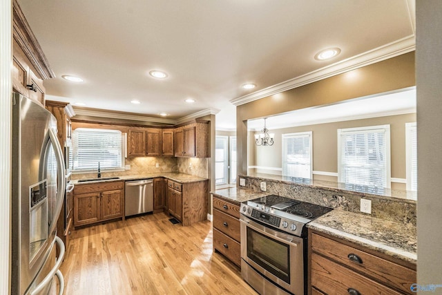 kitchen with decorative backsplash, appliances with stainless steel finishes, ornamental molding, sink, and a notable chandelier