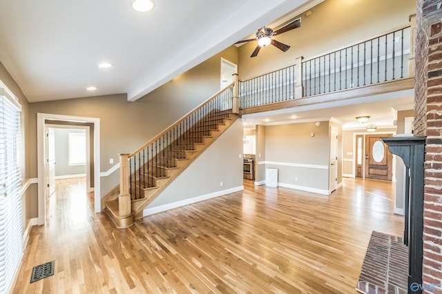 unfurnished living room with ceiling fan, light hardwood / wood-style floors, vaulted ceiling, and a brick fireplace