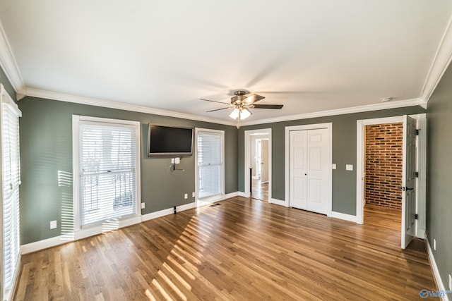 interior space featuring ceiling fan, wood-type flooring, crown molding, and brick wall