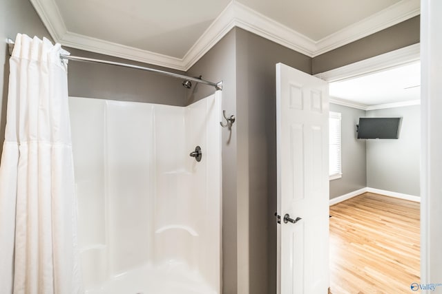 bathroom featuring a shower with shower curtain, hardwood / wood-style floors, and ornamental molding