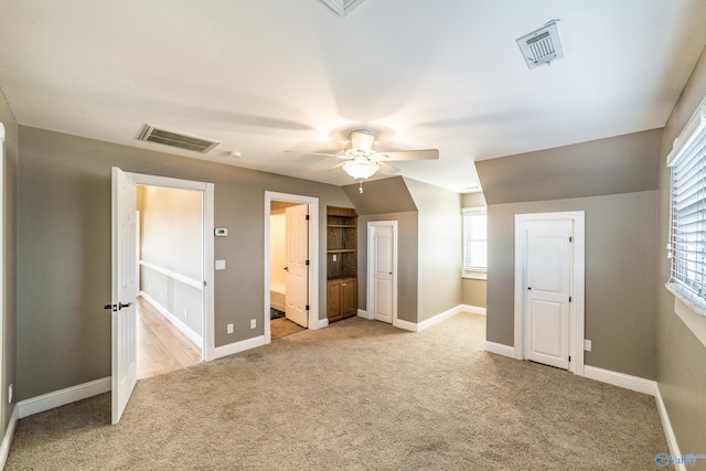 interior space featuring ceiling fan, lofted ceiling, light carpet, and connected bathroom