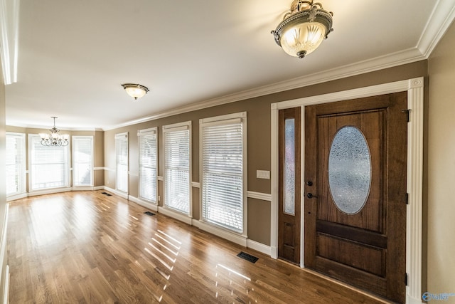 foyer featuring hardwood / wood-style floors, an inviting chandelier, and crown molding