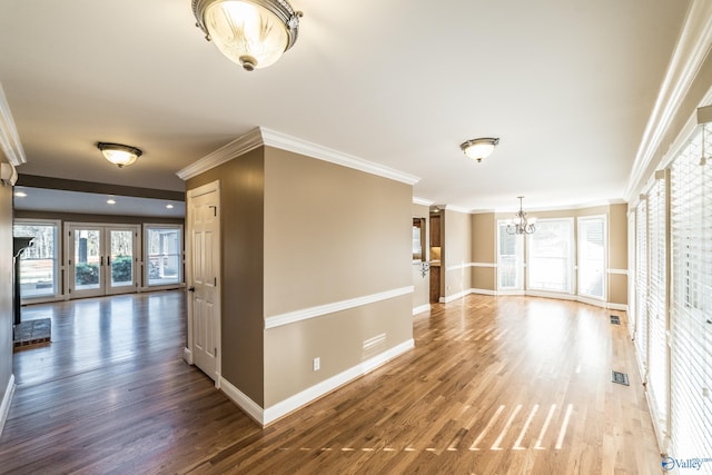 corridor featuring hardwood / wood-style floors, french doors, crown molding, and an inviting chandelier