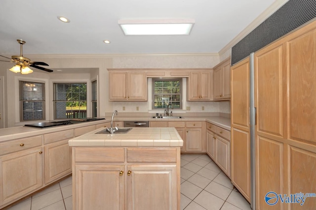 kitchen with paneled built in fridge, a center island with sink, a healthy amount of sunlight, and tile counters