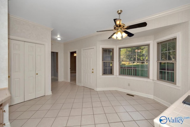 unfurnished dining area with ceiling fan, ornamental molding, and light tile patterned floors