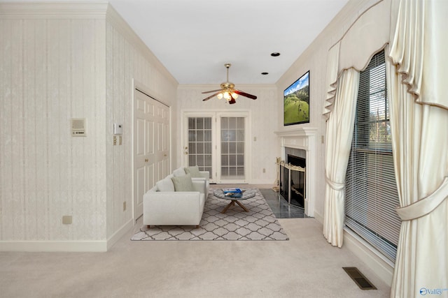 living room with ceiling fan, crown molding, and light colored carpet